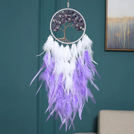 Decorative dreamcatcher with purple and white feathers hanging against a teal wall.