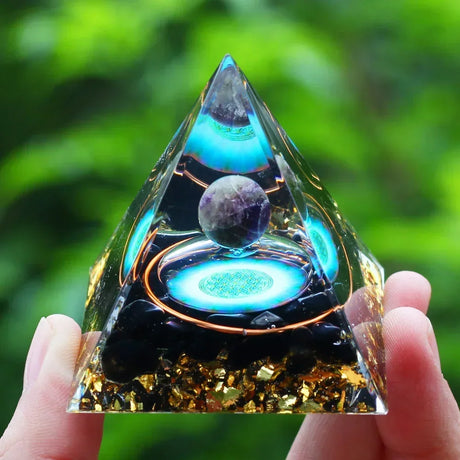 Triangular crystal with glowing blue center held by a hand against a blurred green background