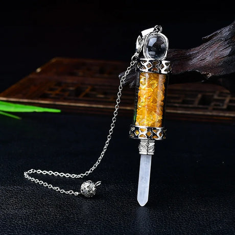 Decorative object with amber-colored interior and silver chain on a dark background