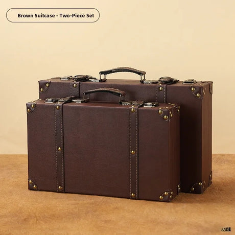 Two brown suitcases with gold studs on a beige background
