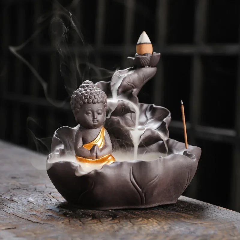 Incense burner shaped like a lotus with a Buddha figure, emitting smoke.