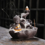 Incense burner shaped like a lotus with a Buddha figure, emitting smoke.