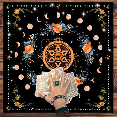 Hand holding tarot cards with a star symbol and floral design on a black background