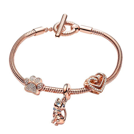 Rose gold bracelet with paw print and heart charm on a white background