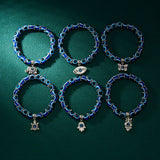 Set of five blue beaded bracelets with various charms on a dark green background