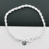 Silver braided bracelet with a charm on a white surface