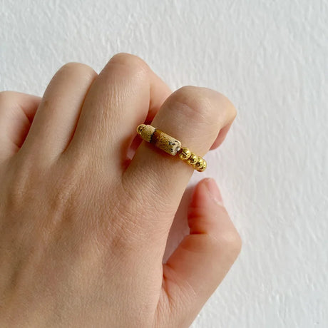 Gold ring on a person's finger against a white background