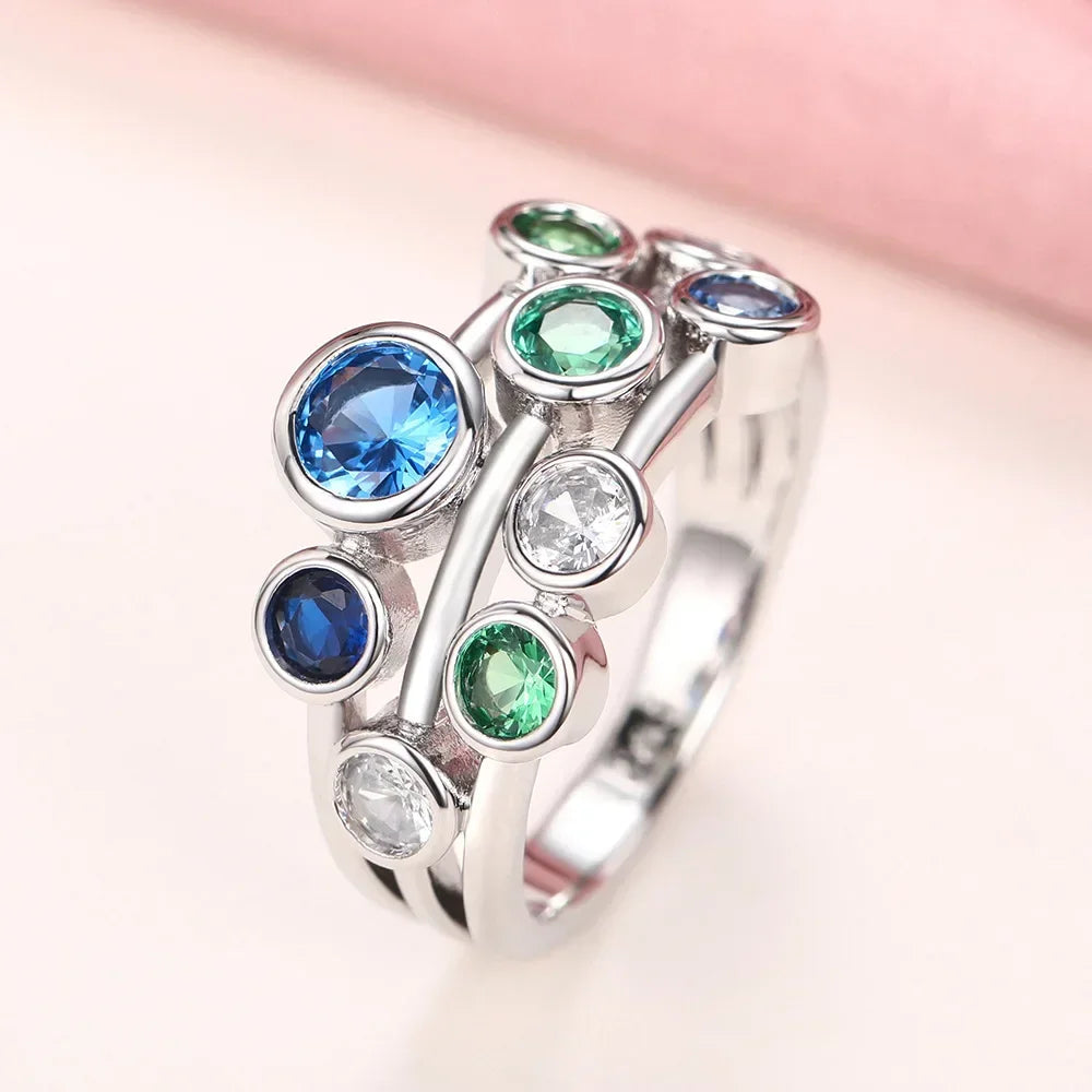 Silver ring with multicolored gemstones on a soft pink background