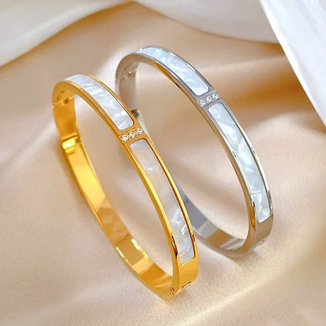 Two gold and silver bangles on a beige surface
