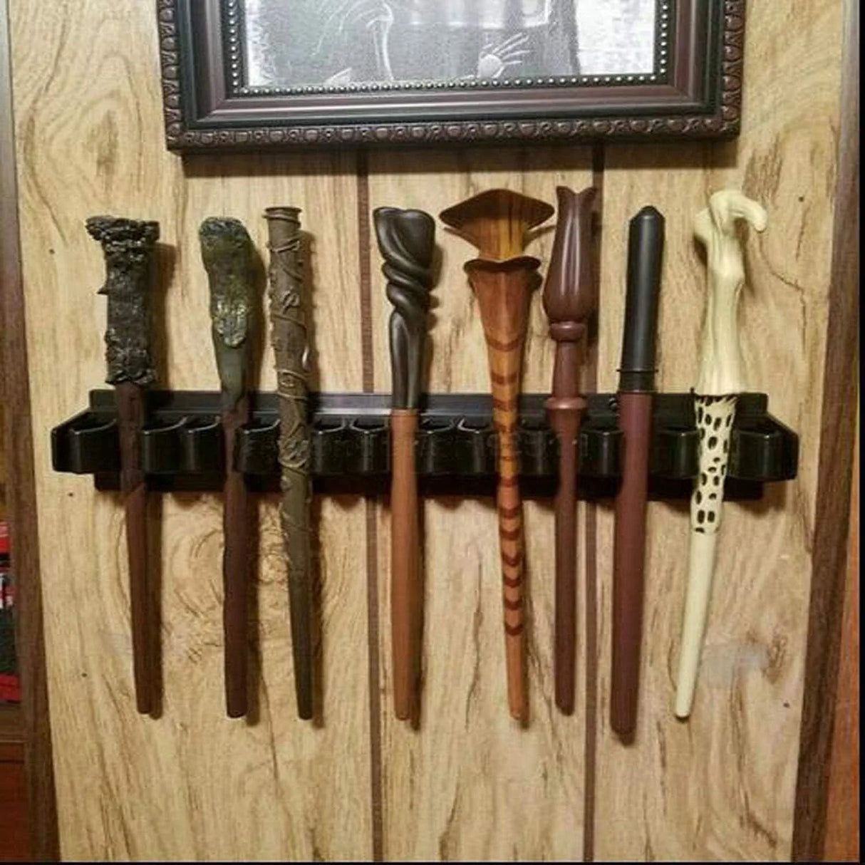 Collection of wooden wands on a holder against a wooden wall.