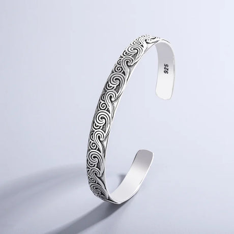 Silver bracelet with intricate patterns on a light gray background
