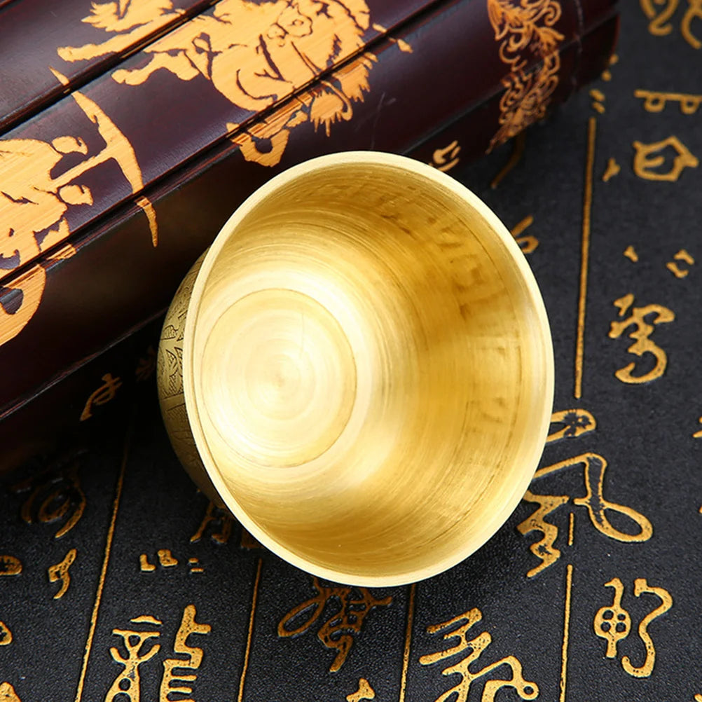Gold cup on a dark surface with gold text and patterns