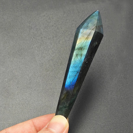 Multicolored crystal held by a hand against a gray background