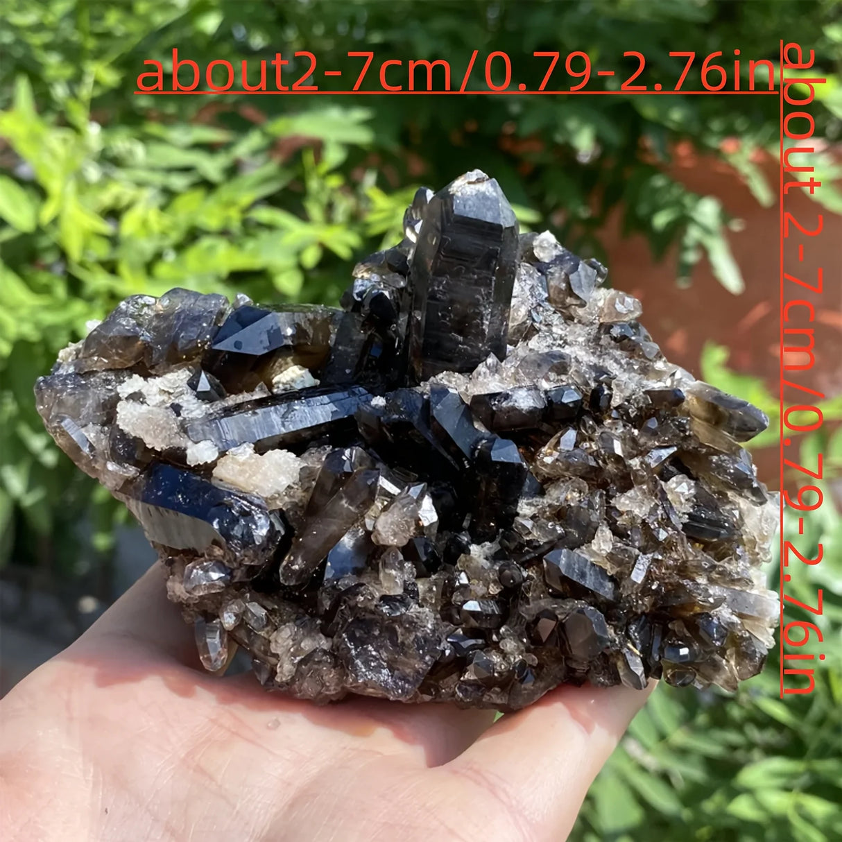 Mineral specimen held in hand with greenery in the background