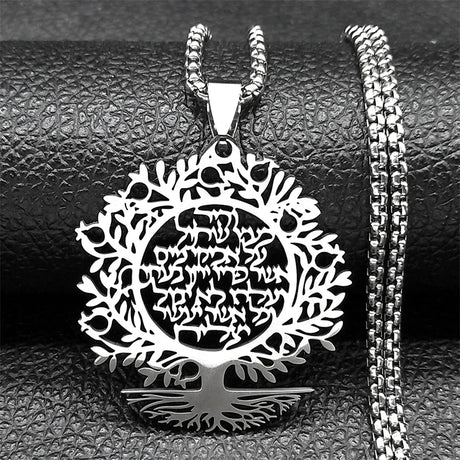 Silver tree-shaped pendant with engraved design on a textured black surface