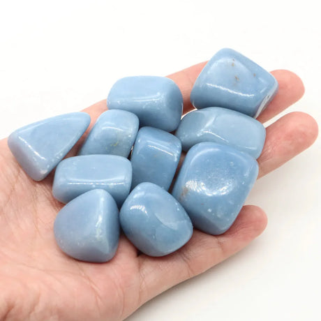 Hand holding blue tumbled stones against a white background