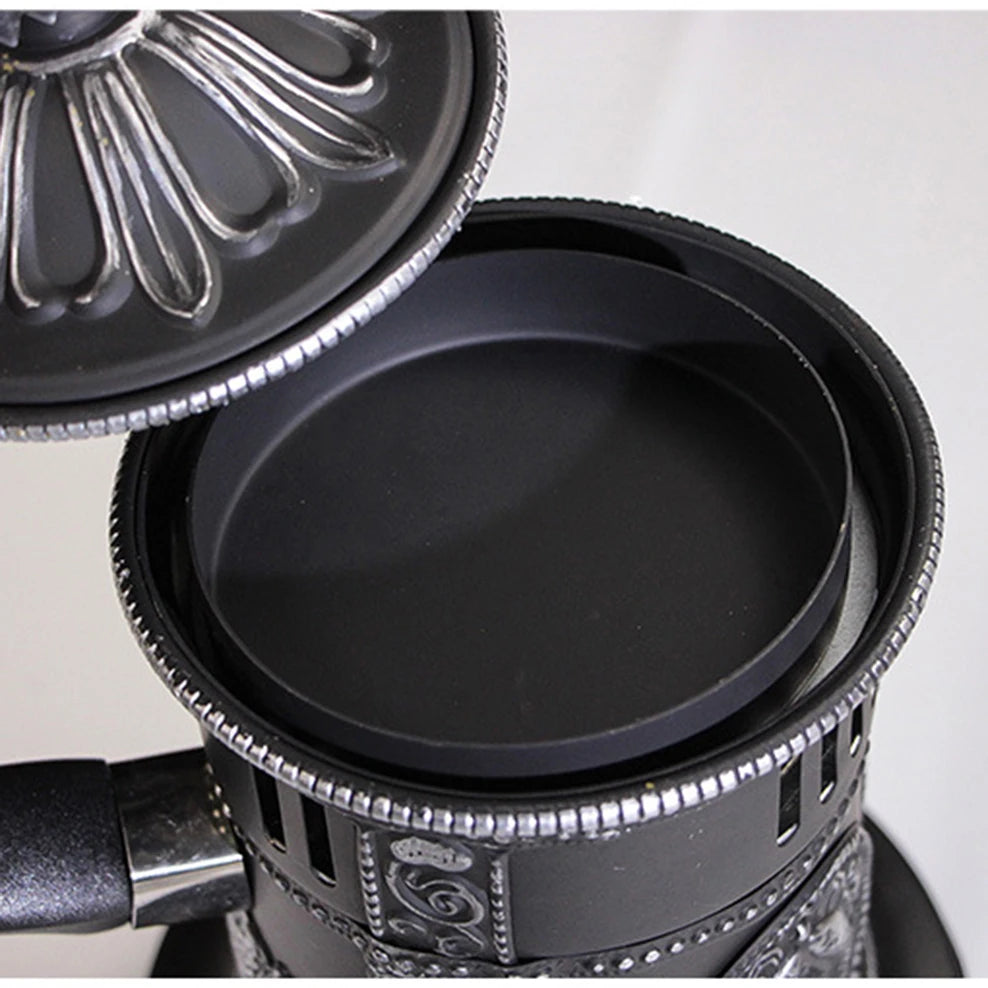 Close-up of a black frying pan with decorative handle on a light gray background