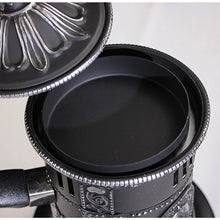 Close-up of a black frying pan with decorative handle on a light gray background