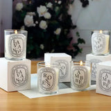 Candles with labels on a wooden surface with a blurred floral background