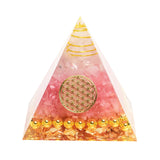 Pyramid-shaped object with pink and gold design on a white background