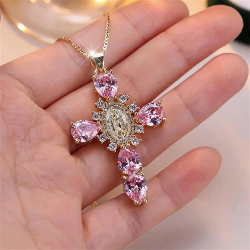 Gold necklace with pink gemstone pendant held in a hand