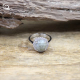 Silver ring with a green stone on a wooden surface