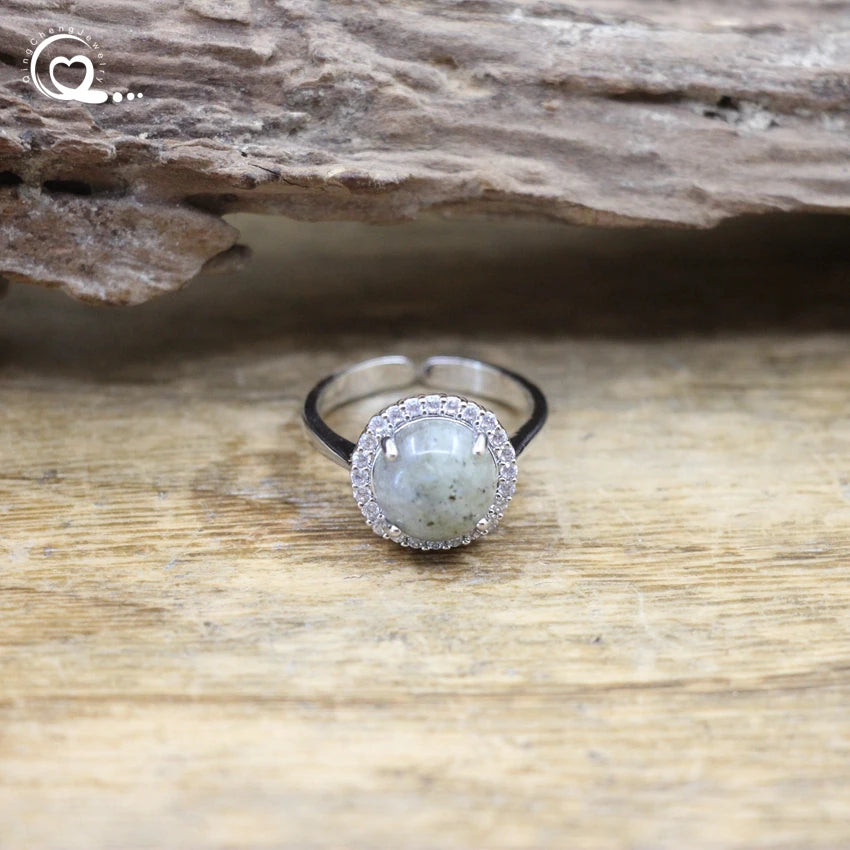 Silver ring with a green stone on a wooden surface