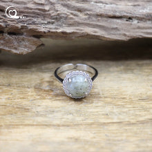 Silver ring with a green stone on a wooden surface