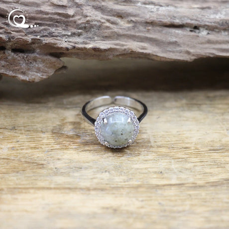 Silver ring with a green stone on a wooden surface