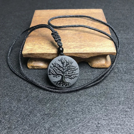 Necklace with a tree of life pendant on a wooden block against a gray background