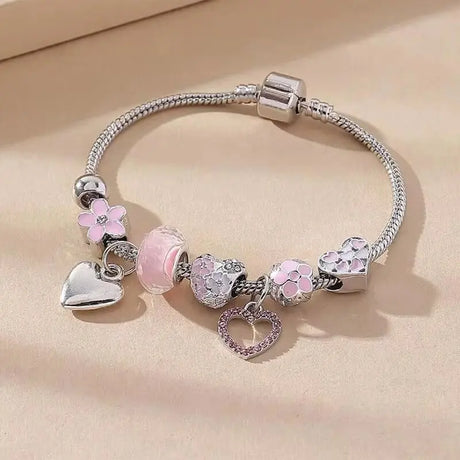 Silver bracelet with heart and flower charms on a beige background