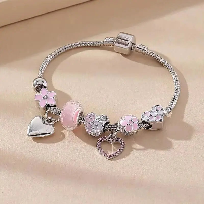 Silver bracelet with heart and flower charms on a beige background