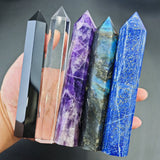 Five crystal points of different colors held in a hand against a dark background