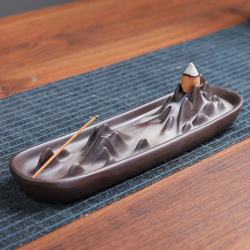 Ceramic incense burner with mountain design on a wooden surface