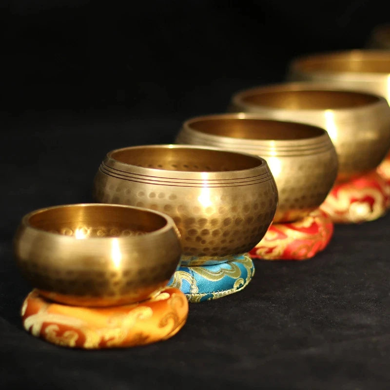 Set of gold singing bowls on colorful stands against a dark background