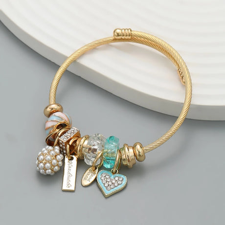 Gold bracelet with various charms on a gray surface