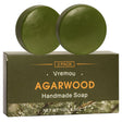 Two green agarwood handmade soap bars on a Vremou branded box with a white background.