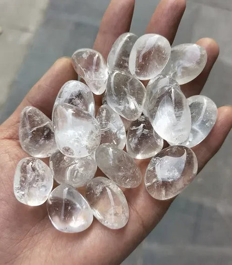 Hand holding clear crystal stones against a blurred background