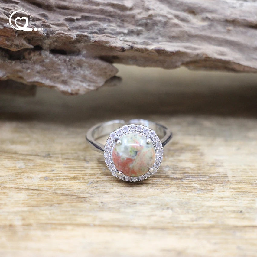 Silver ring with a large gemstone and smaller stones on a wooden surface