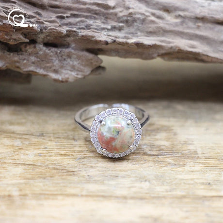 Silver ring with a large gemstone and smaller stones on a wooden surface