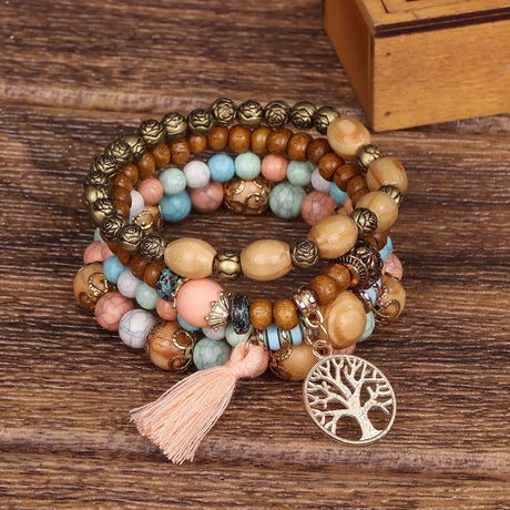 Multicolored beaded bracelet with tassel and tree of life charm on a wooden surface