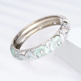 Silver bracelet with floral design on a white background