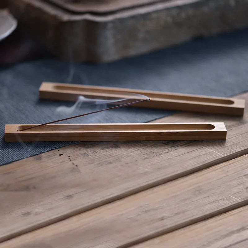 Wooden incense burner with burning incense on a wooden surface