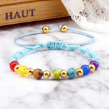 Colorful beaded bracelet on a marble surface with 'HAUT' text in the background