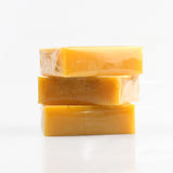 Three bars of yellow soap stacked on a white background