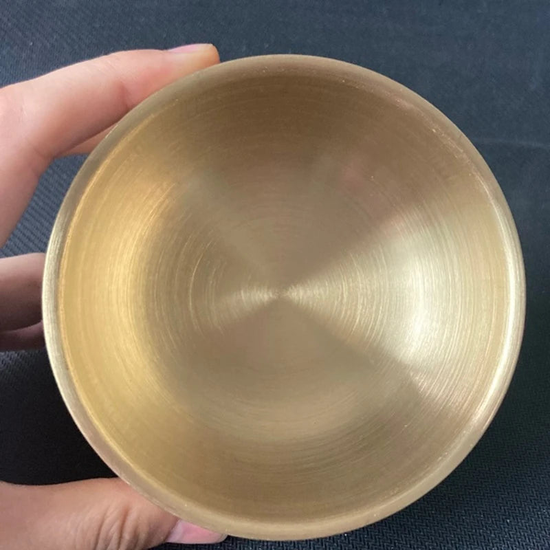 Hand holding a gold bowl against a dark background