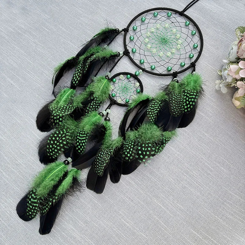 Black and green dreamcatcher with feathers on a light gray background