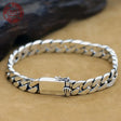 Silver chain bracelet on a beige surface with a brand logo in the corner.