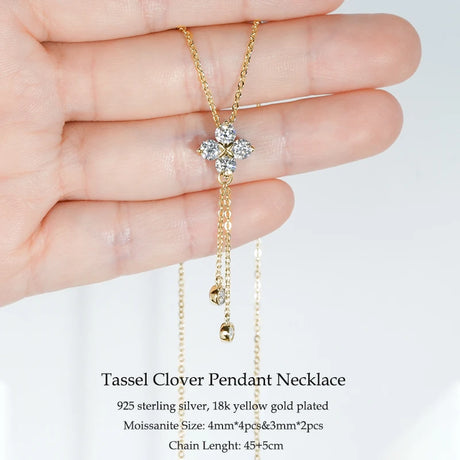 Gold tassel clover pendant necklace held in a hand with product details on a white background
