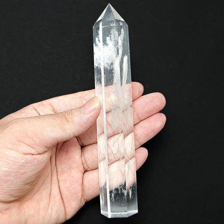 Clear crystal tower held in a hand against a black background